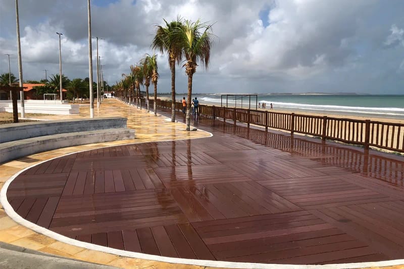 Praça pública à beira-mar com deck circular em madeira ecológica EcoÚtil entre coqueiros