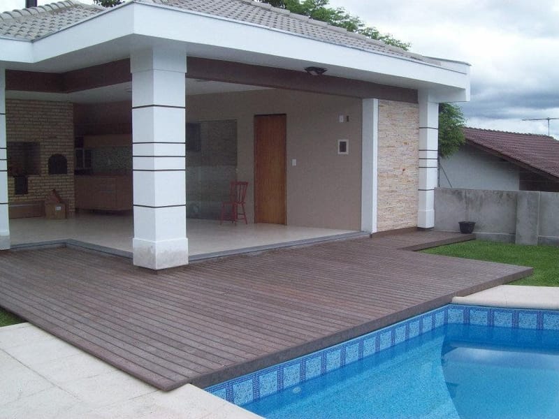 Deck de piscina em madeira plástica maciça ligando a casa da piscina ao jardim