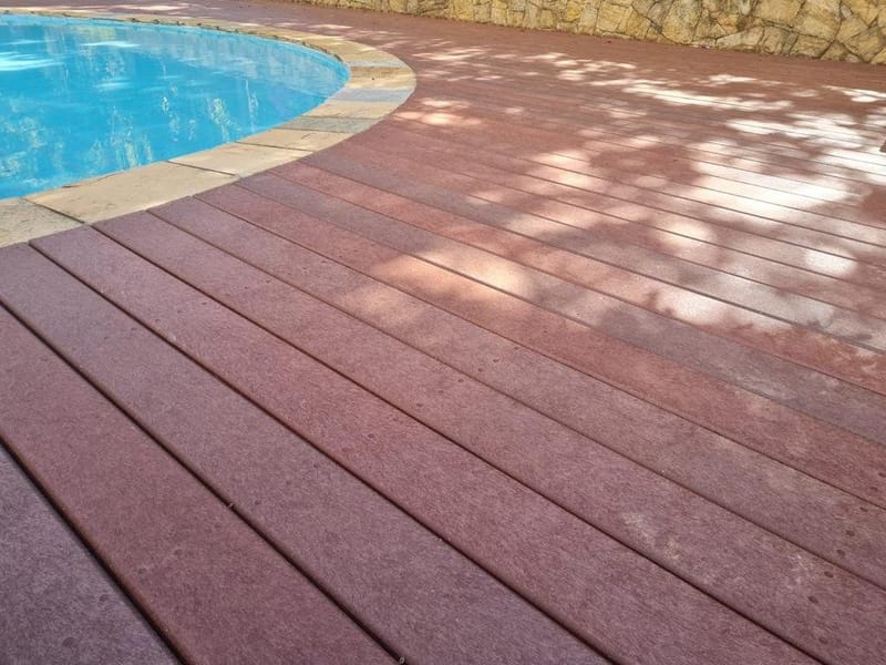 Deck de madeira plástica maciça contornando piscina de borda curva