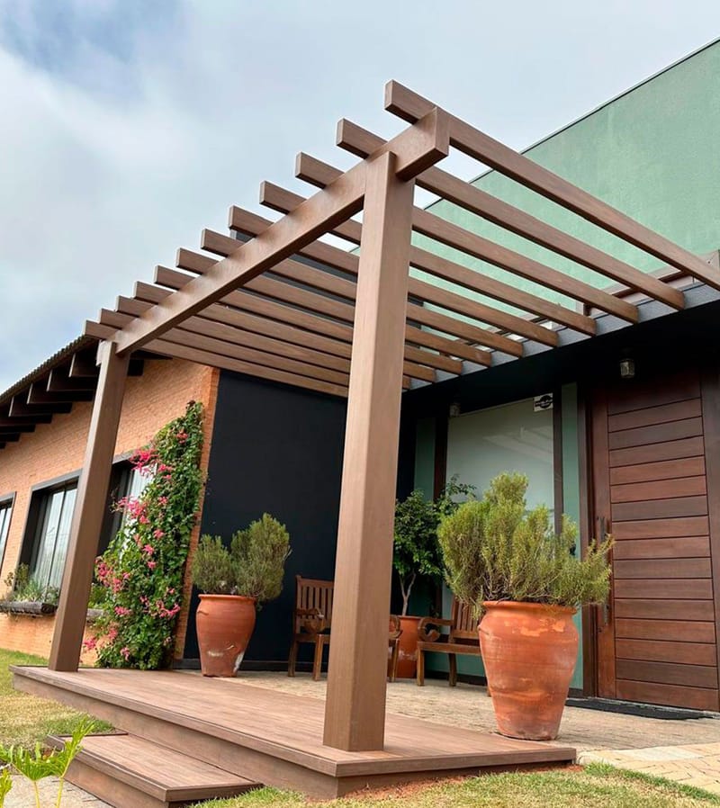 Pergolado Linha Prime sobre deck na entrada de uma casa com jardim