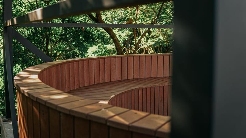 Banco curvo de madeira ecológica sob as árvores