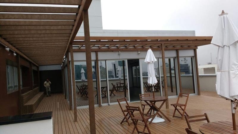 Pergolado de madeira ecológica em rooftop comercial com mesas
