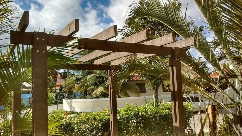 Pergolado de madeira ecológica em jardim residencial com trepadeira