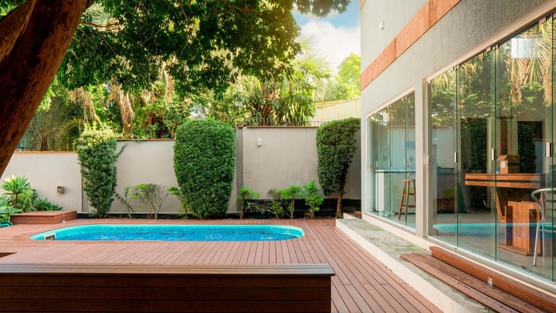 Deck de madeira ecológica entre a casa envidraçada e a piscina