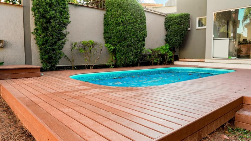 Deck amplo de madeira ecológica contornando piscina em casa de alto padrão